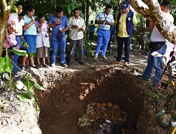 2019年11月6日，薩爾瓦多卡卡佩拉（Cacaopera）的Yancolo小村莊，國際法醫小組挖掘出1981年內戰大屠殺時的受害者屍體，人們在可能屬於其親屬的遺體周圍祈禱。1981年薩爾瓦多內戰期間的一次軍事行動中有800名平民喪生。（Photo by MARVIN RECINOS / AFP）