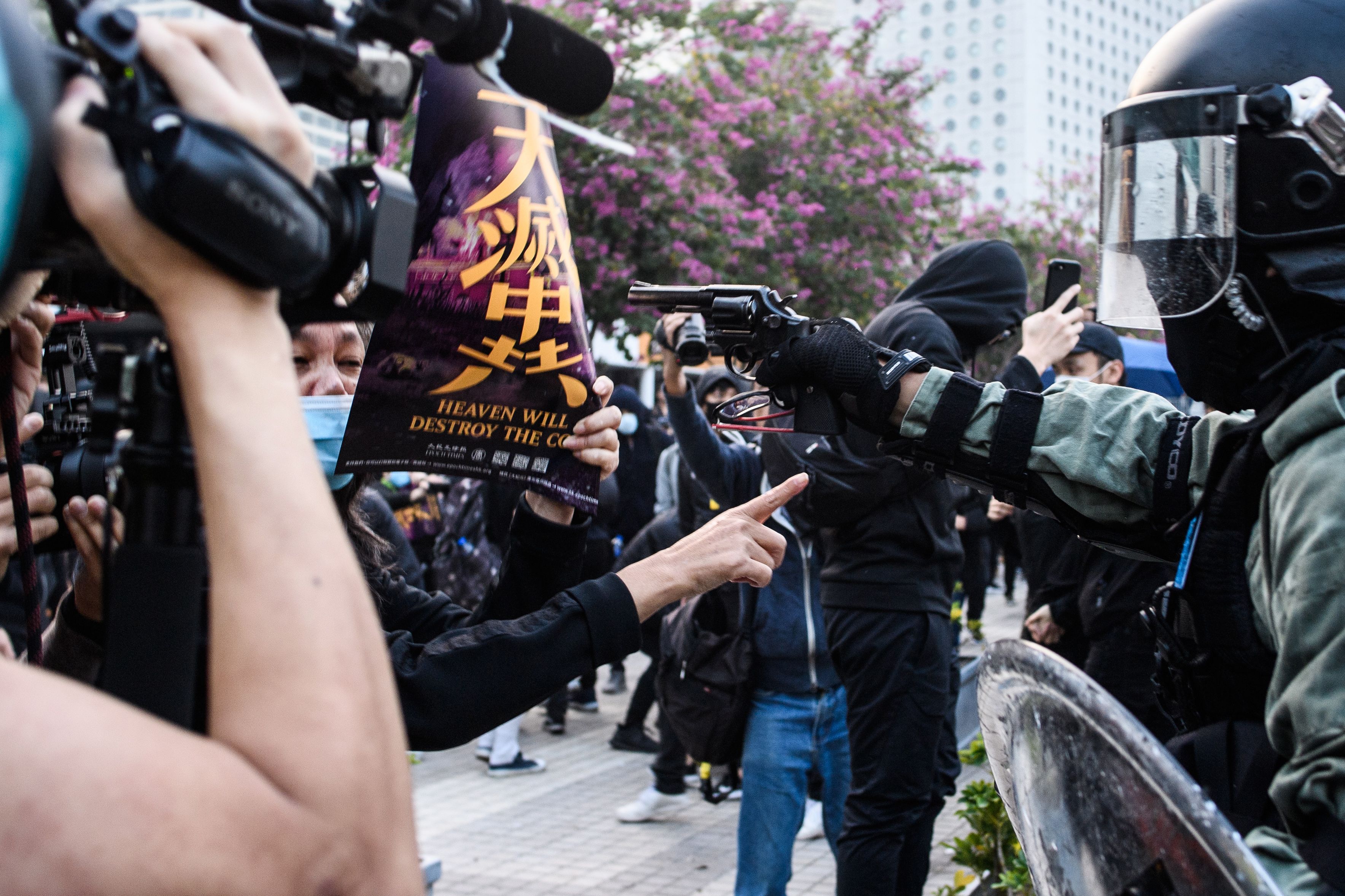 2019年12月22日,香港市民集會支持新疆維吾爾族人,隨後遭防暴警察暴力驅散,一名警察更一度舉槍指向一名高舉「天滅中共」海報的婦女。(ANTHONY WALLACE/AFP via Getty Images)