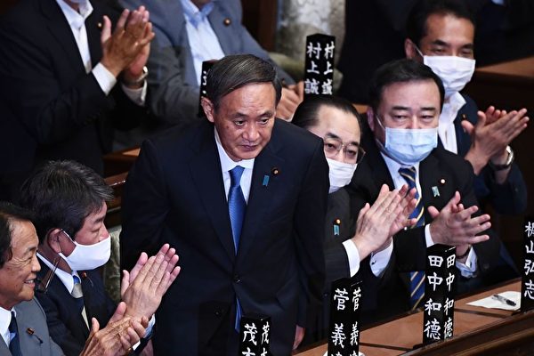 圖為菅義偉（前立者）9月16日獲國會確認擔任日本首相，議員鼓掌祝賀。（AFP via Getty Images）