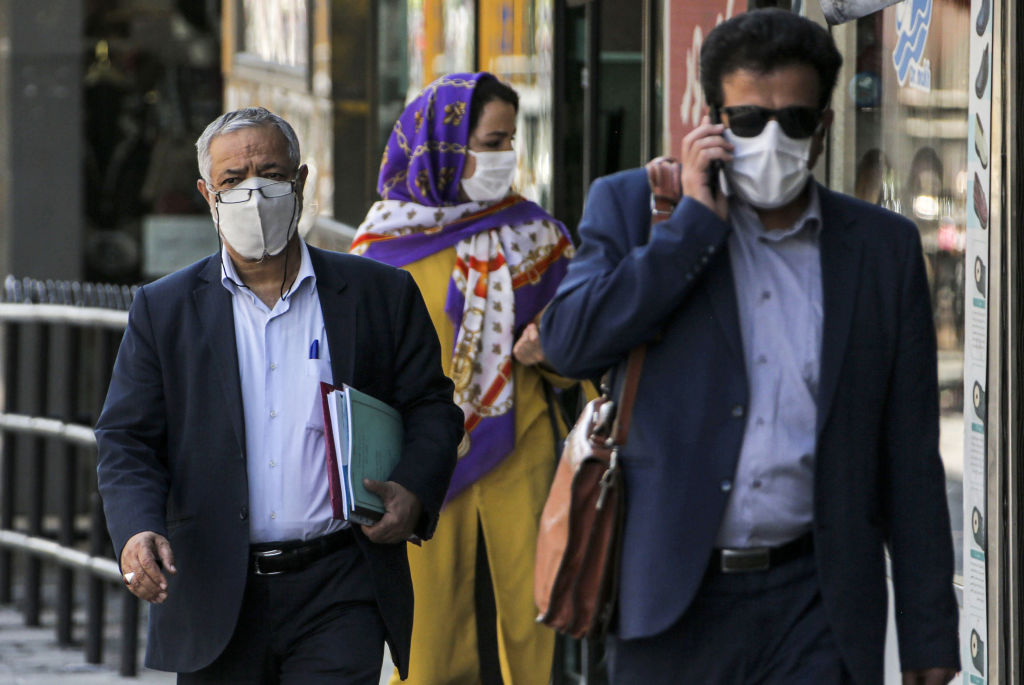 9月27日,在伊朗首都德黑兰的街头,人们戴着口罩经过商店。(ATTA KENARE/AFP via Getty Images)