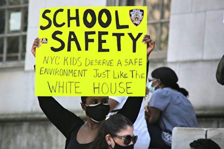 非裔家長手舉標語，表示學校的環境應像白宮一樣安全，給學生安全的學習環境。