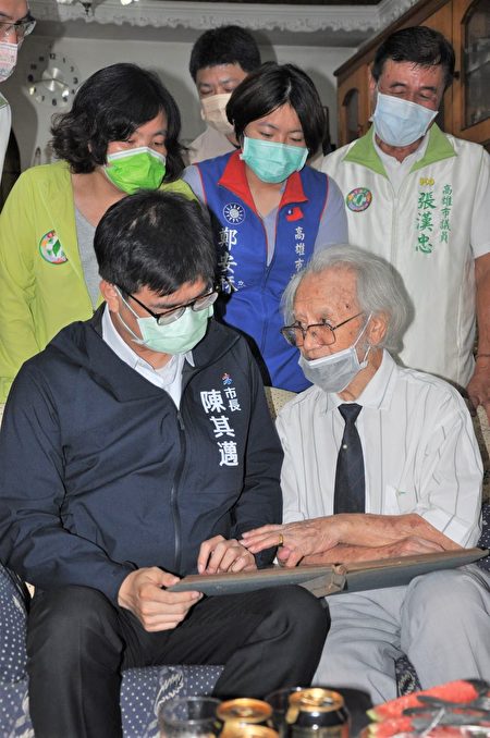 高雄市长陈其迈与百岁人瑞王德永，一同欣赏王爷爷亲自拍摄的老相片。