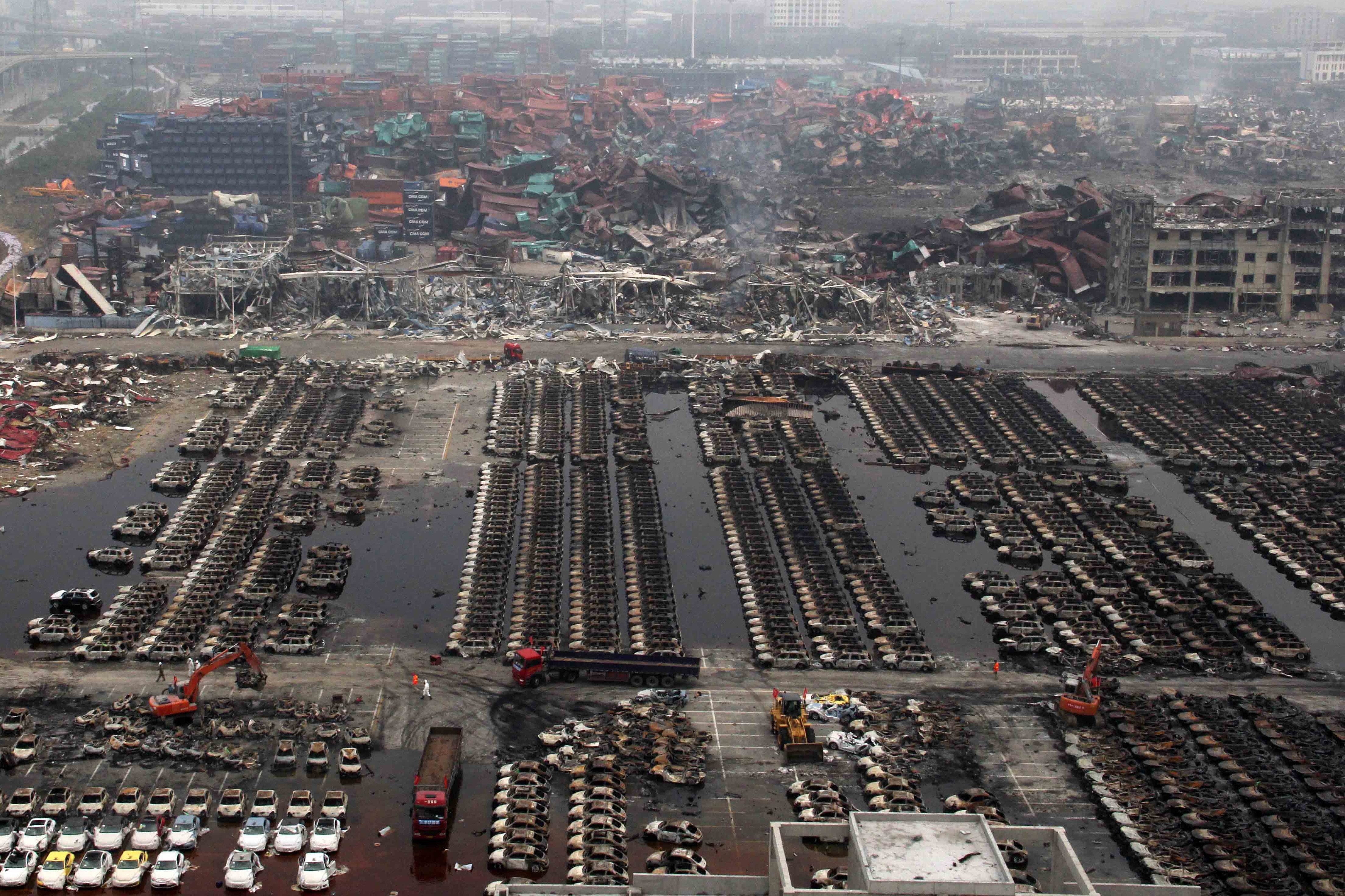 2015年8月20日，天津滨海新区开发区瑞海公司危险品仓库发生两次大爆炸后，挖掘机在清理受损的汽车。(STR/AFP via Getty Images)