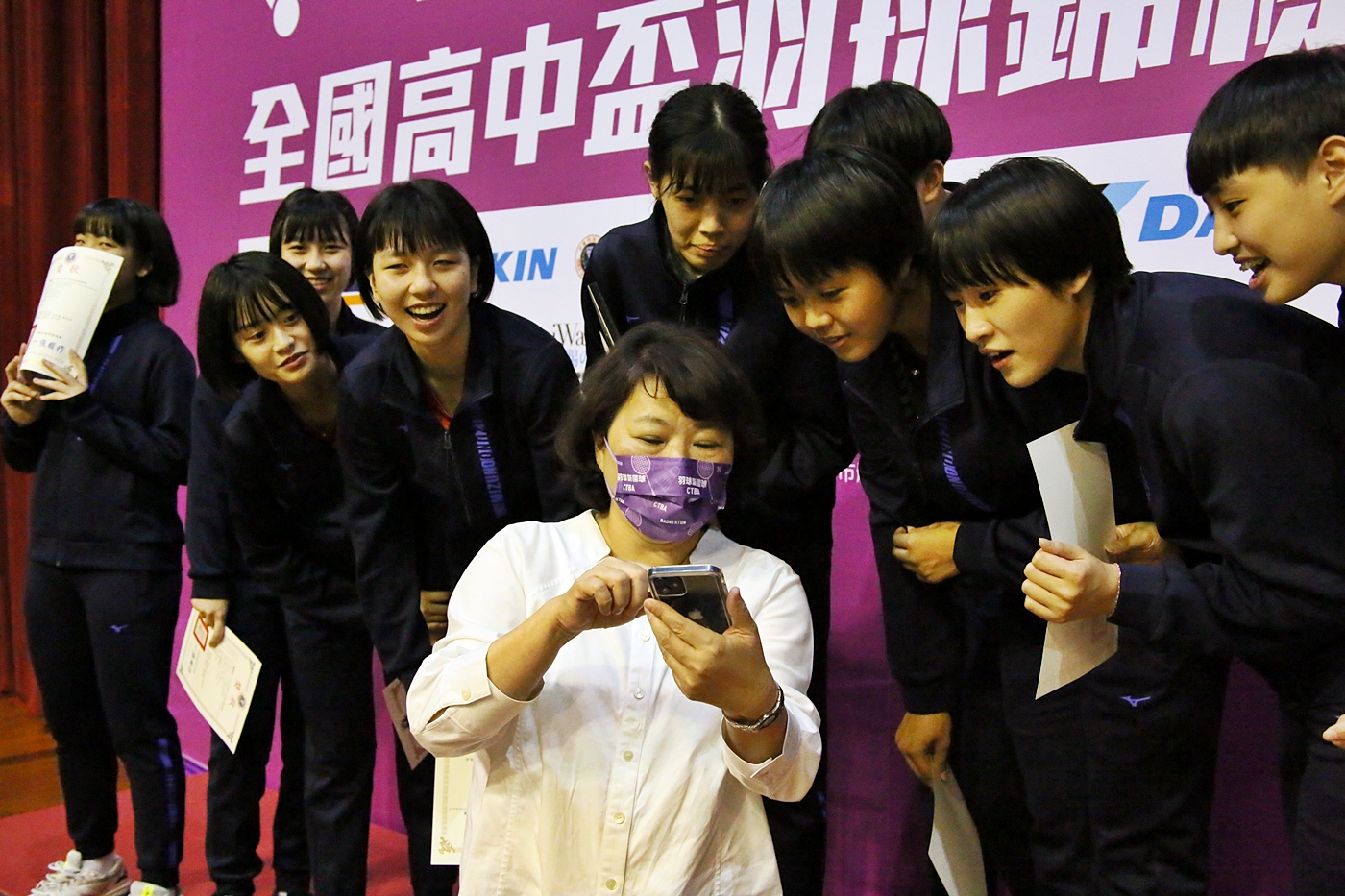 市长黄敏惠与女团选手一起看APP。
