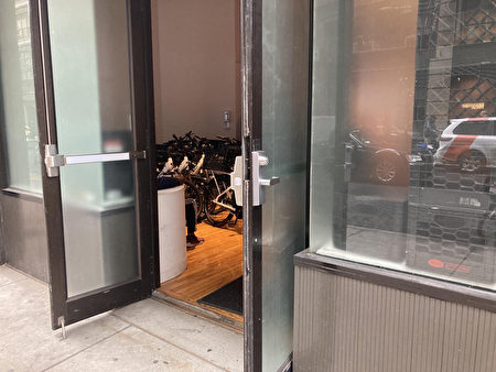 曼哈顿25街西125号一家杂货配送中心，隐约可见一名送货员和一排自行车在店门口。