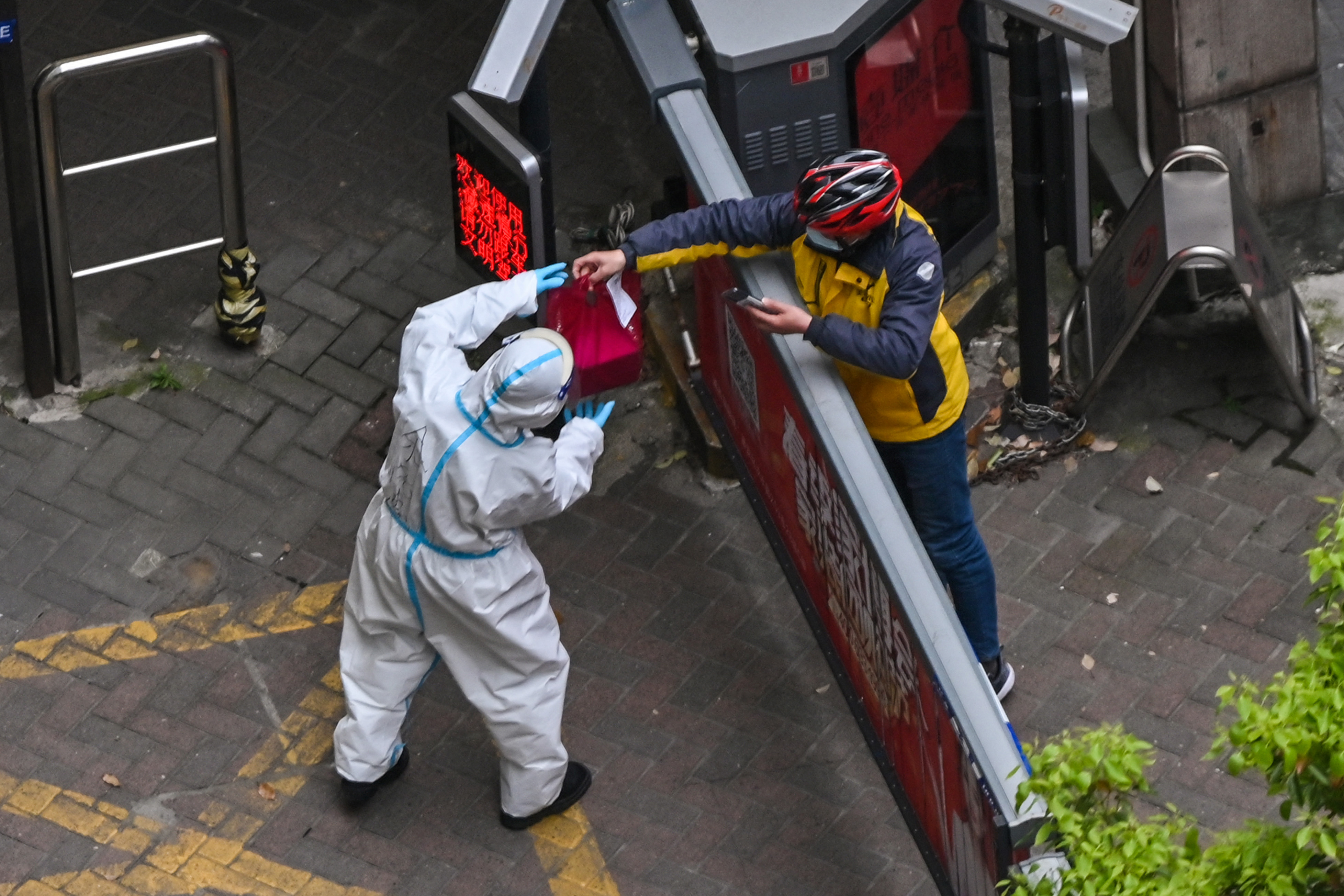 圖為2022年4月5日,上海靜安區封控第二階段,身穿防護服的工作人員在大院入口處接收貨品。(Hector Retamal/FP)
