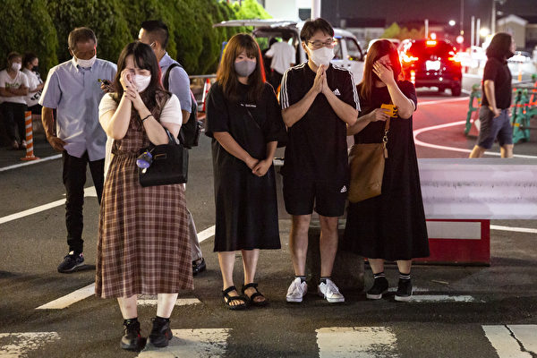 2022年7月8日，日本前首相安倍晉三在日本奈良被暗殺後，人們在當地一個車站外祈禱和哭泣。（Yuichi Yamazaki/Getty Images）