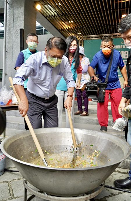 屏东县长潘孟安与专业厨师一同制作粄条料理，将大把肉燥、芹菜和鱿鱼以及粄条轮番下锅，现场香味四溢。 