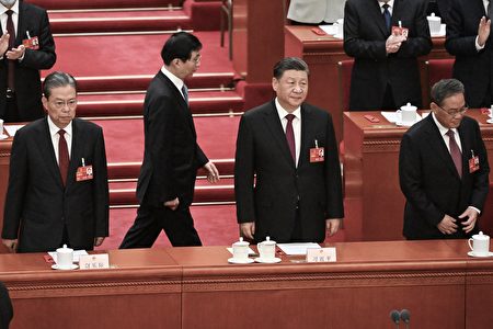 2023年3月10日，中共兩會上，習近平（右二）、李強（右一）、趙樂際（左一）站在主席台上，王滬寧（左二，後排）從後面經過。（NOEL CELIS/AFP via Getty Images）