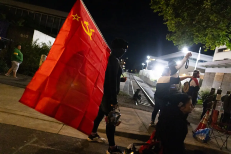 2025年10月4日,一名女子在俄勒冈州波特兰的移民与海关执法局(ICE)办公室前持共产主义旗帜。(John Fredricks/大纪元)