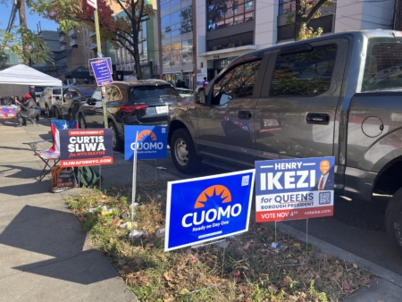 人行道上插著三位市長候選人的廣告牌。