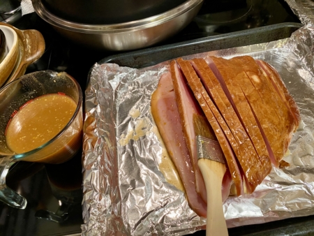 烤箱預熱至375℉。烤盤內放入火腿，每一片火腿塗上汁液。