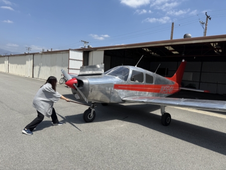 一名女學員將小飛機從機庫中拉出;這架銀灰色飛機是Sky用於培訓學生的教學機。