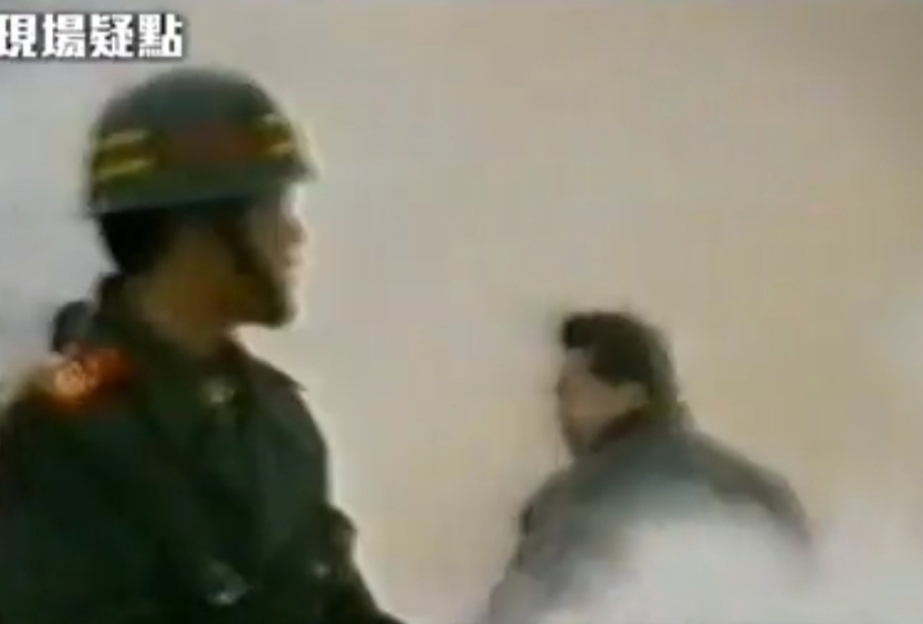 圖片說明:看!這就是目擊者證言說的那個「壯碩的軍警」。目測此人三十多歲,體型夠壯夠碩,濃髮前沿兒上蹶,戴眼鏡,穿軍大衣,正從東向西走離開事發現場,因殺人而驚魂未定,身形仍可見一秒鐘前用力掄動重物的姿勢。值勤武警在觀察周圍動靜。