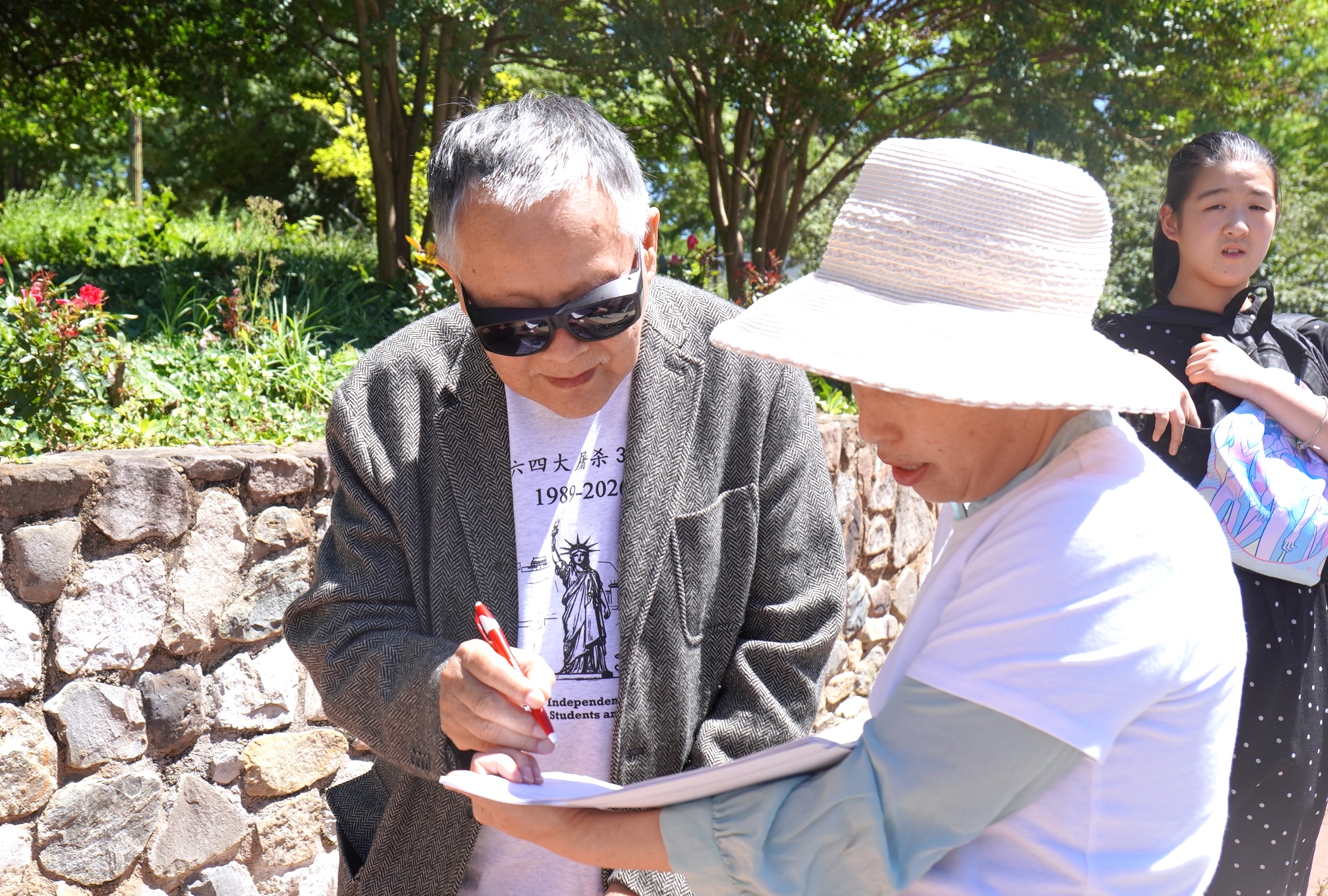 2026年5月30日,六四民主運動的標誌性人物魏京生(左)在呼籲美國參議院通過《法輪功與活摘器官受害者保護法案》的請願書上簽名。(李辰/大紀元)
