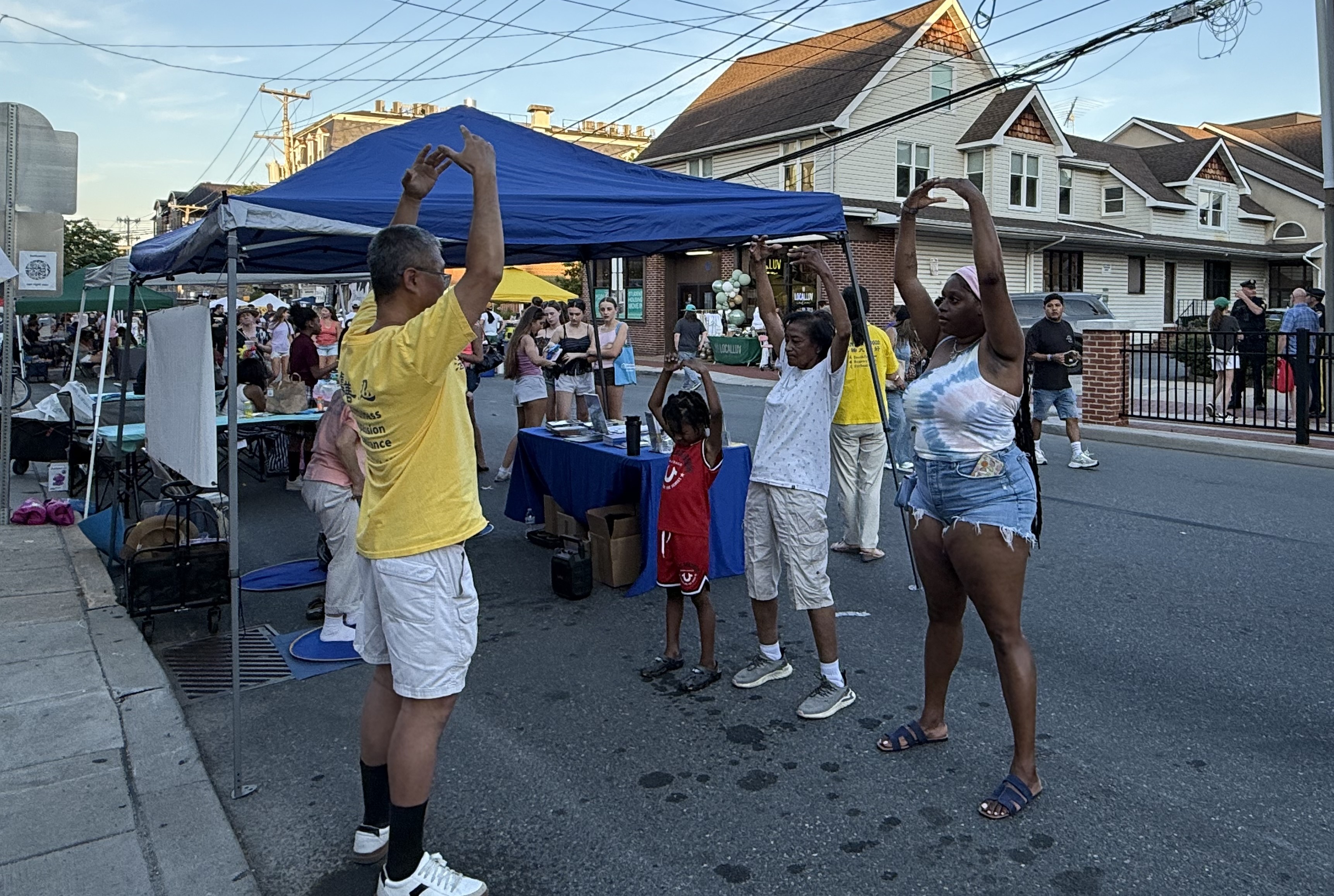 2026年6月5日晚,特拉華州紐瓦克市舉辦「紐瓦克之夜」(Newark Nite),心理健康諮詢師布列塔尼·柯林斯(Brittany Collins)當天與母親和孩子一起學煉了法輪功功法。(楊茜/大紀元)