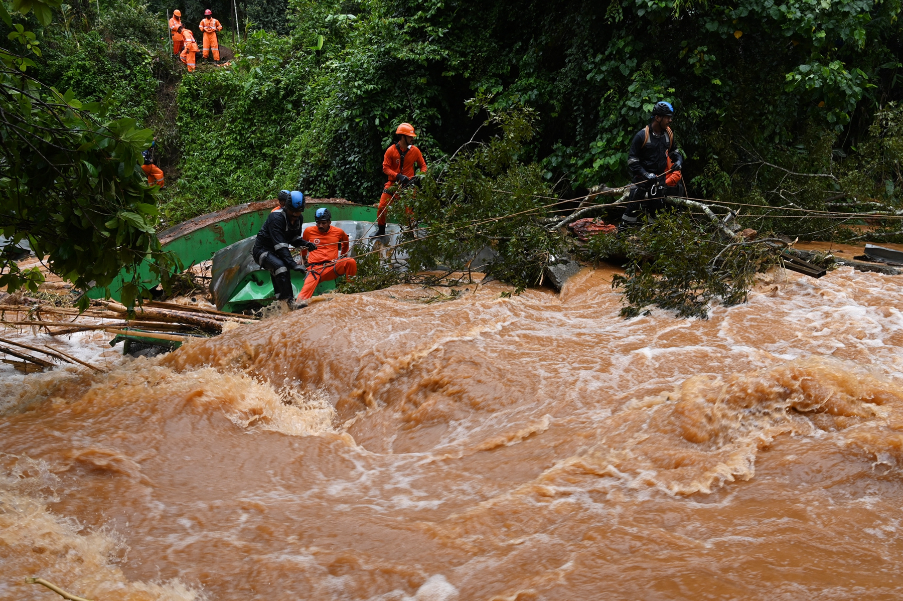 2026年7月8日,印度喀拉拉邦瓦亞納德縣(Wayanad)因暴雨引發山體滑坡後,救援人員在洪水猛漲期間,清除被連根拔起的樹木。(RJ Mathew/AFP via Getty Images)