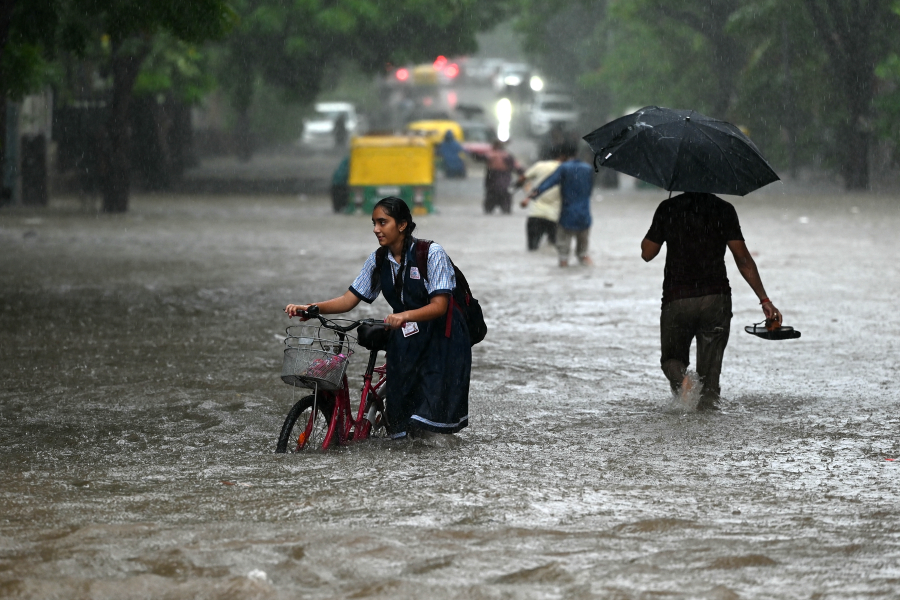 2026年7月23日,印度西部古吉拉特邦最大城市艾哈邁達巴德(Ahmedabad)降下大雨後,民眾被迫涉水而行。(Shammi Mehra/AFP via Getty Images)
