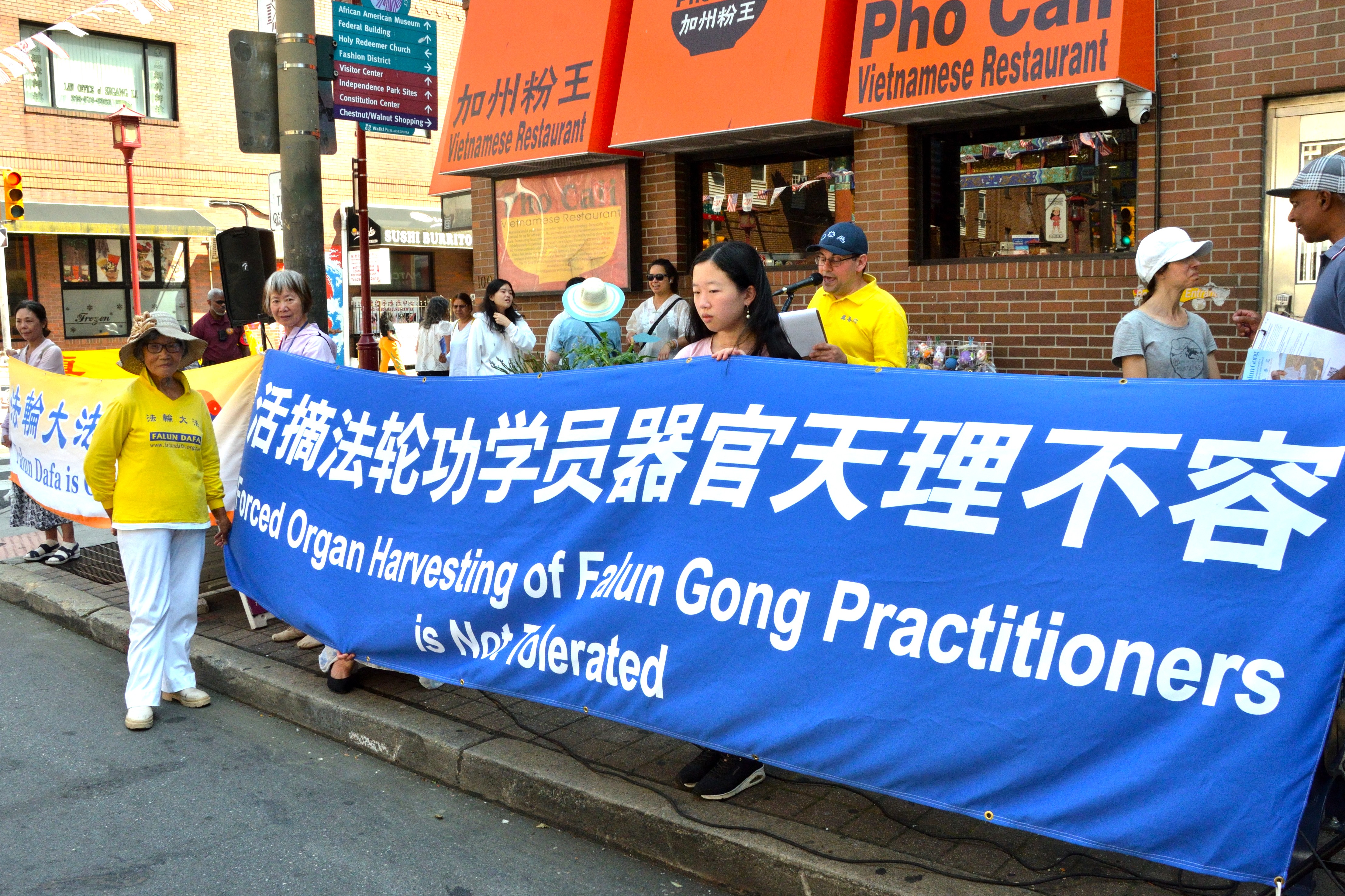 田忠鳳女士(橫幅前)在集會上講述了她在2006年3月在被中共抓捕後險遭活摘器官的親身經歷。(良克霖/大紀元)
