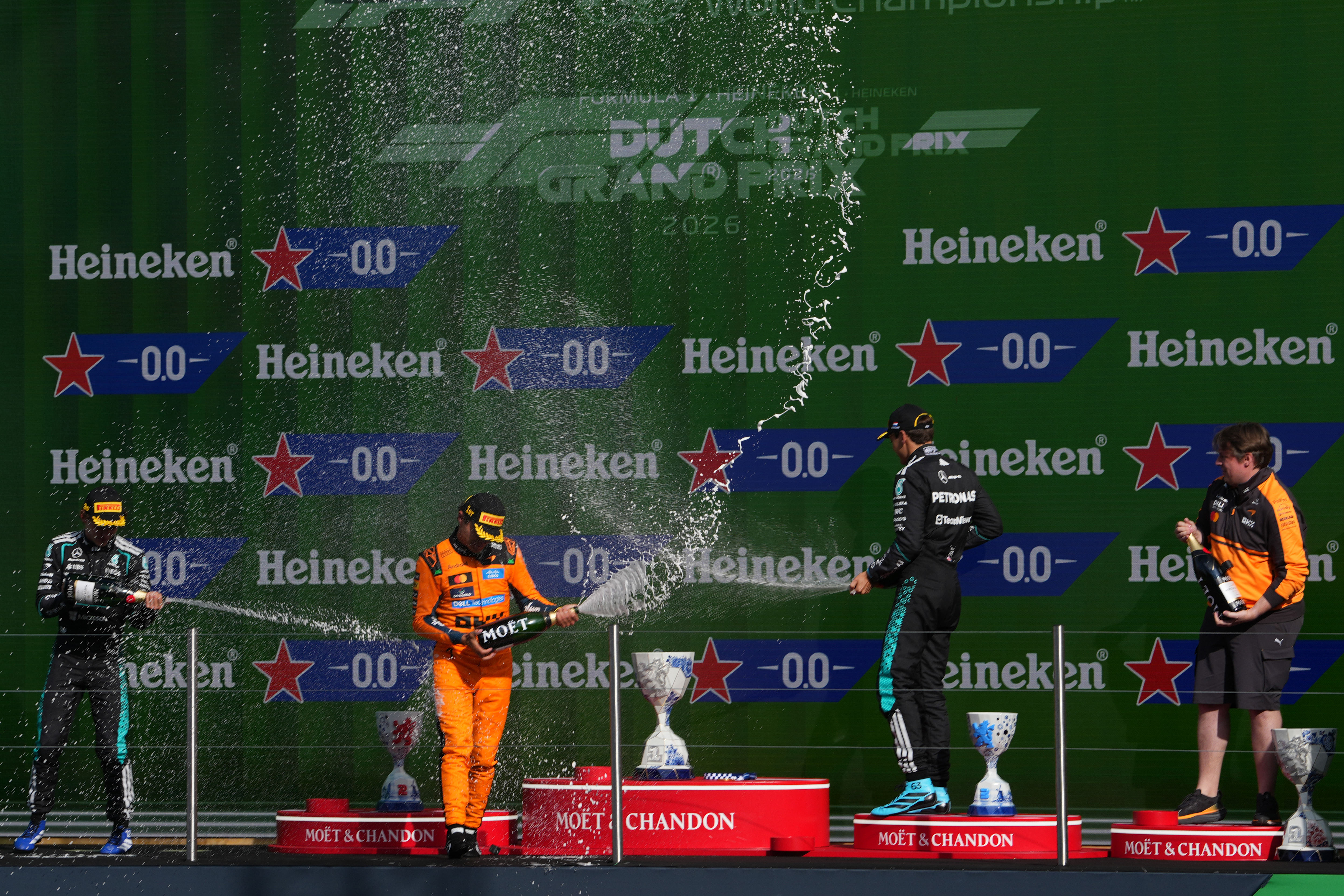 2026年8月23日,F1大獎賽荷蘭站正賽,邁凱倫英國車手諾里斯(Lando Norris、中)桿位發車,率先衝線,連續兩站奪得勝利。兩位梅賽德斯車手——安東內利(左)和拉塞爾分列第二和第三。圖為三人在領獎台上噴灑香檳慶祝瞬間。(Alex Bierens de Haan/Getty Images)