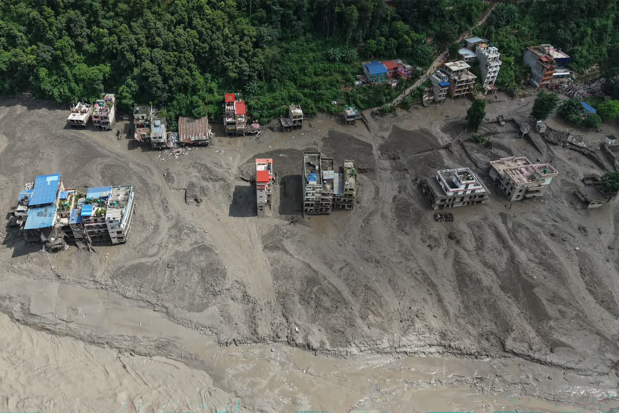 2026年8月26日,尼泊爾努瓦科特縣(Nuwakot)特里蘇里巴扎爾(Trishuli Bazar)發生山洪,河岸邊房屋部分被泥水掩埋。(Prabin Ranabhat/AFP via Getty Images)
