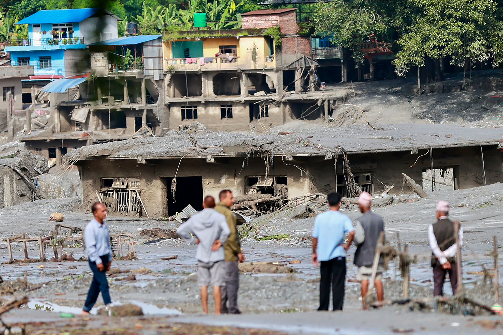 2026年8月27日,尼泊爾努瓦科特縣(Nuwakot)德夫加特(Devghat)的許多房屋被淤泥掩埋,當地民眾聚在一旁觀看。(Prabin Ranabhat/AFP via Getty Images)