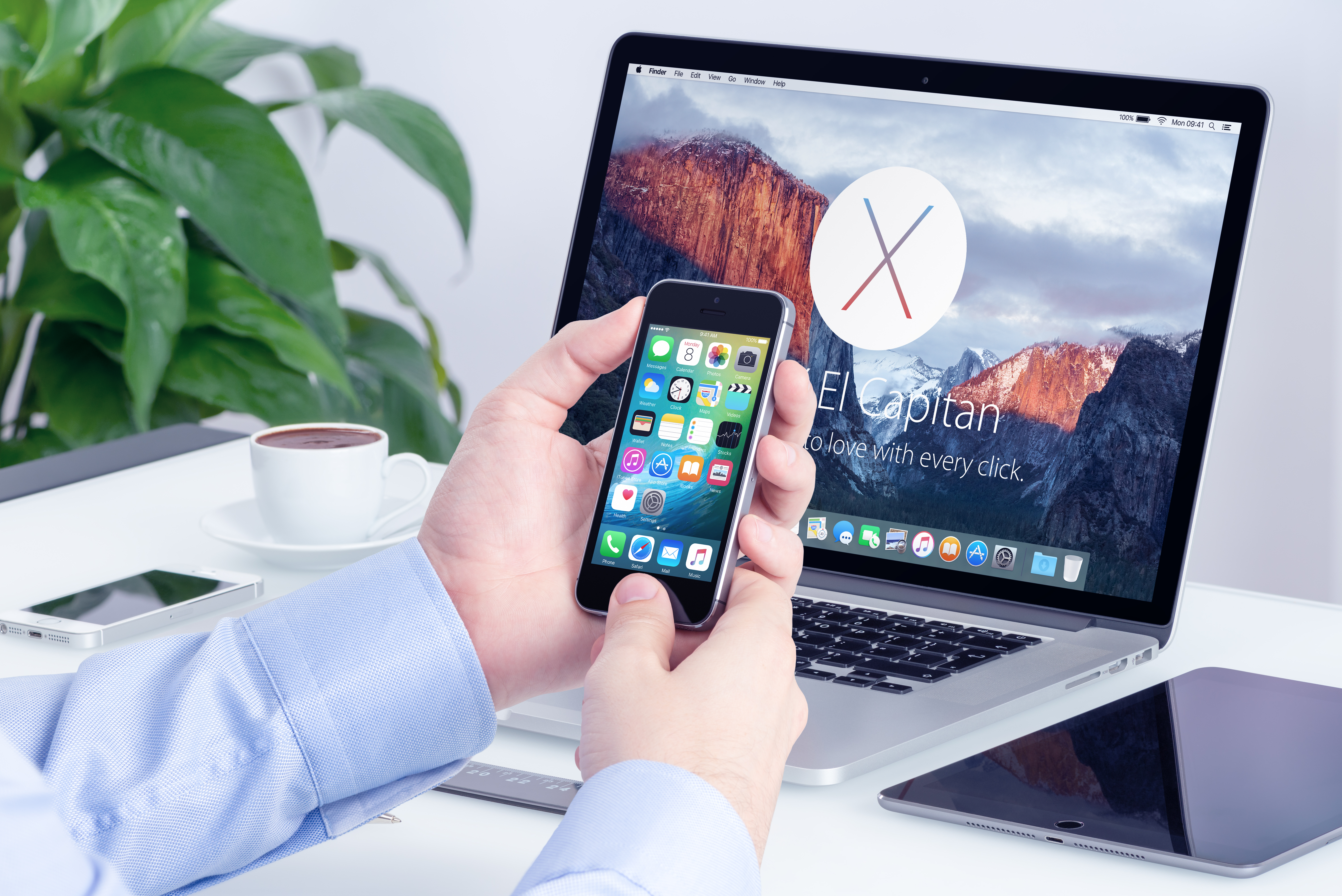 一名男子在使用手機與手提電腦。(Shutterstock)