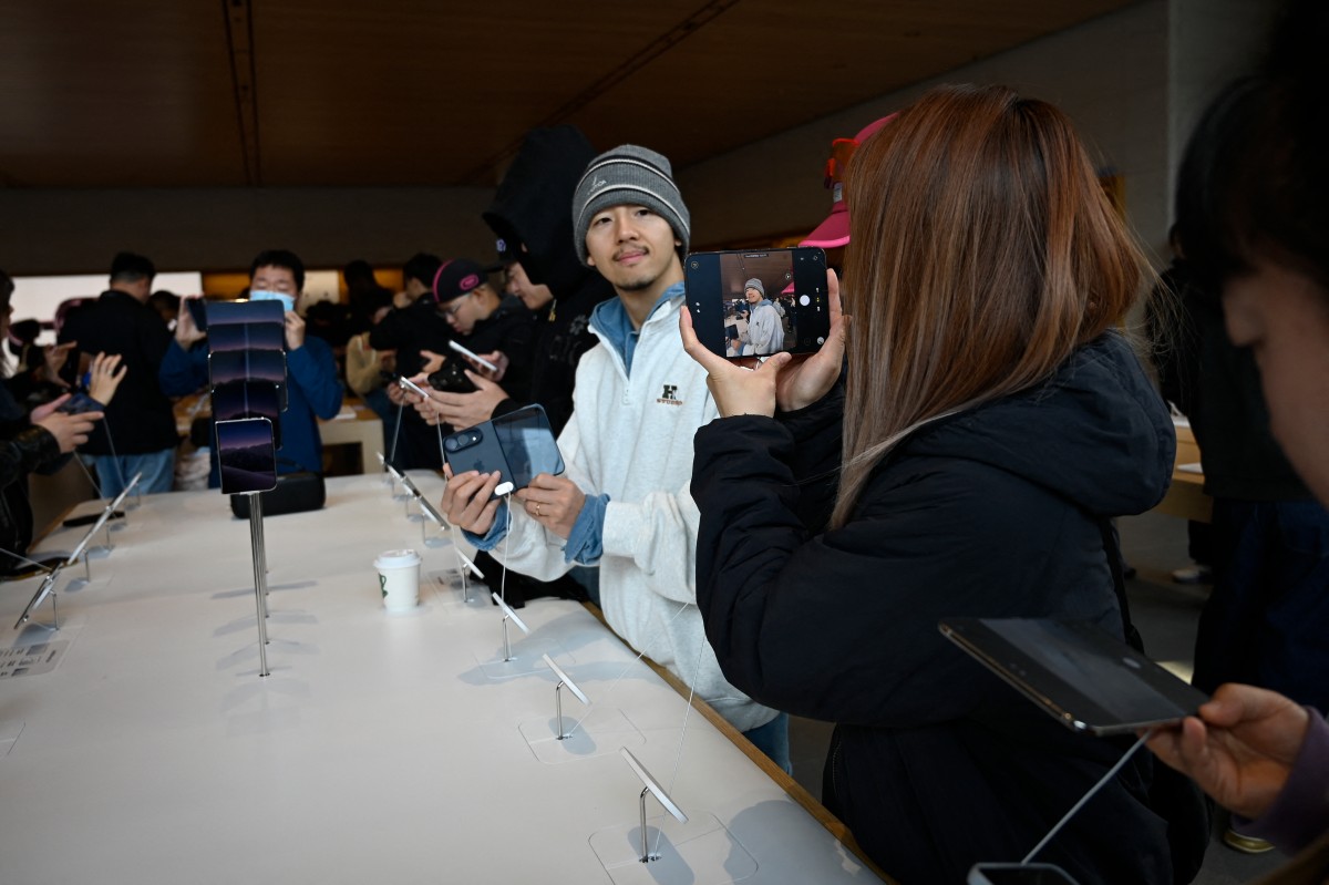 2026年10月23日,人們在北京一家蘋果商店觀看iPhone Duo。 (Photo by WANG Zhao / AFP)
